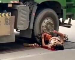 Chinese woman has her legs wedged under a truck