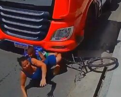 Woman rides her bicycle straight under moving truck