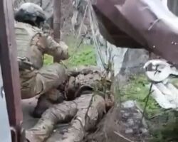 Ukrainian soldiers takes trophy from his fallen Russian enemies