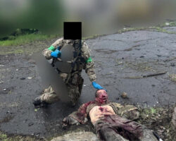 Ukrainian soldier poses with decapitated enemy